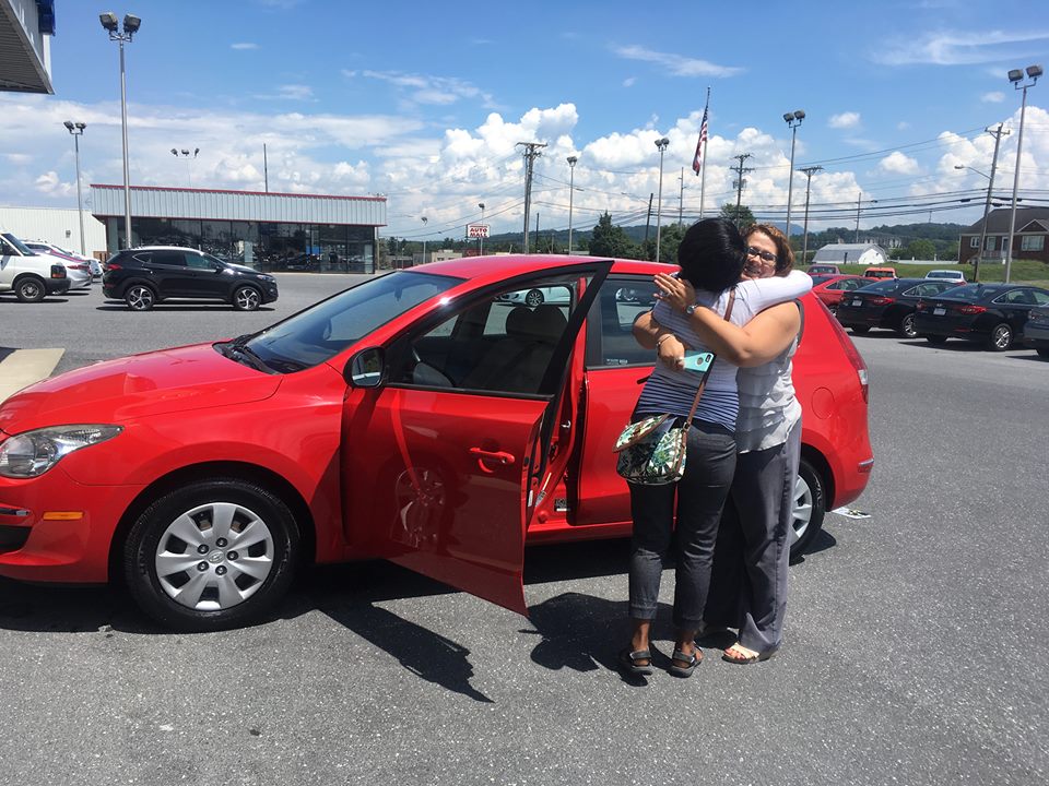 Two people hugging next to a car